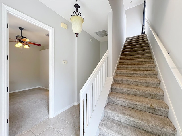 staircase with baseboards, visible vents, ceiling fan, tile patterned floors, and carpet flooring