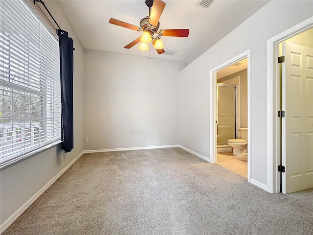 carpeted spare room with visible vents, a ceiling fan, and baseboards