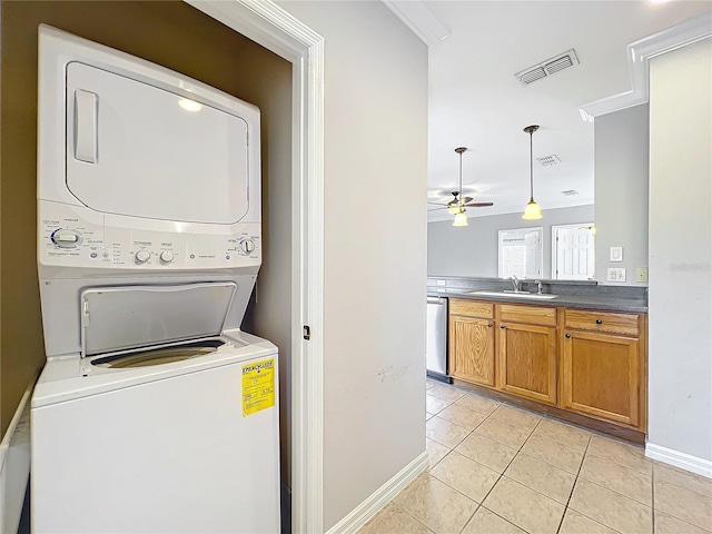 laundry room with light tile patterned floors, visible vents, stacked washing maching and dryer, and a sink