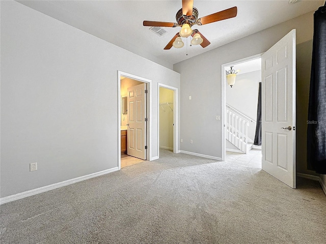 unfurnished bedroom featuring visible vents, light colored carpet, a walk in closet, and baseboards