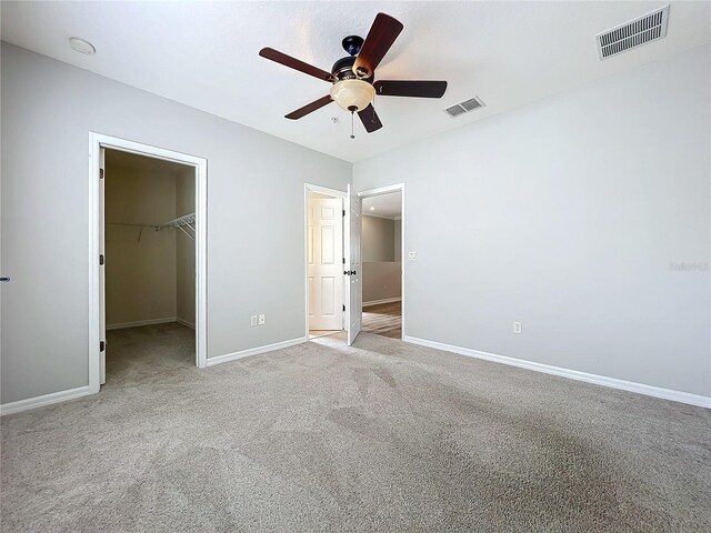 unfurnished bedroom with visible vents, baseboards, carpet floors, and a spacious closet