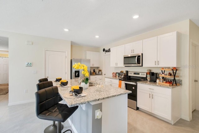 kitchen featuring white cabinetry, a center island with sink, a kitchen breakfast bar, and appliances with stainless steel finishes