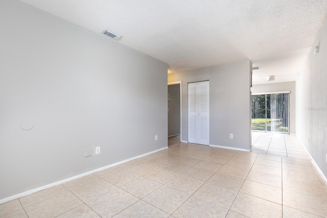 tiled empty room with a textured ceiling