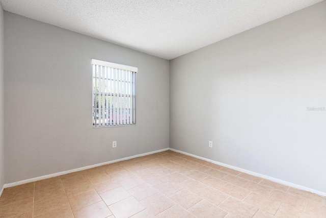 spare room featuring a textured ceiling and light tile patterned floors