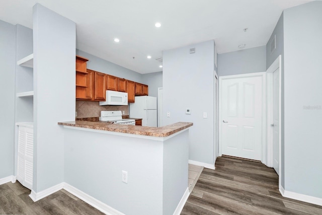 kitchen featuring white appliances, dark hardwood / wood-style floors, kitchen peninsula, and backsplash