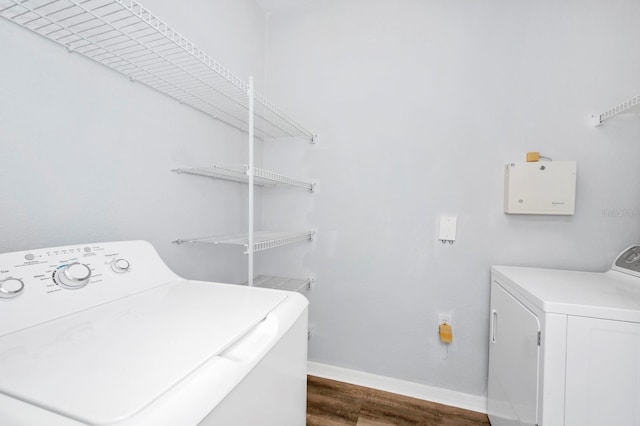 laundry room with washing machine and clothes dryer and dark hardwood / wood-style floors