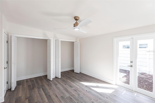 unfurnished bedroom featuring dark hardwood / wood-style flooring, ceiling fan, french doors, and multiple closets