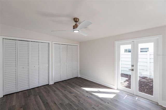 unfurnished bedroom with vaulted ceiling, dark hardwood / wood-style floors, ceiling fan, multiple closets, and french doors