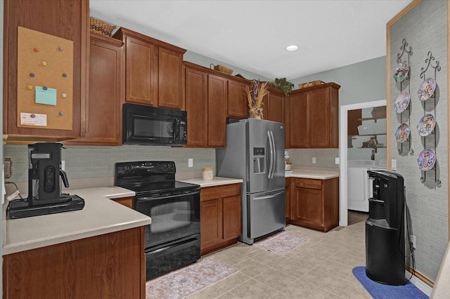 kitchen with tasteful backsplash, light tile patterned floors, black appliances, and washing machine and clothes dryer