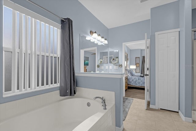 bathroom with tiled tub and tile patterned floors