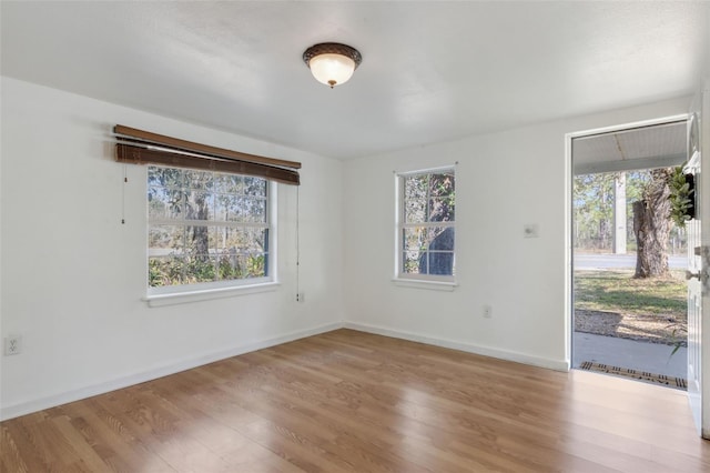 spare room featuring baseboards, wood finished floors, and a healthy amount of sunlight