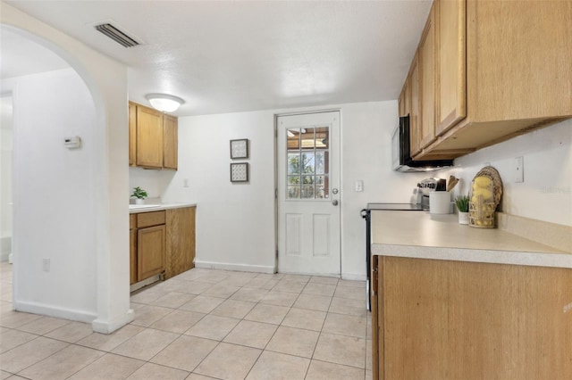 kitchen featuring baseboards, visible vents, stainless steel electric range, light countertops, and light tile patterned flooring