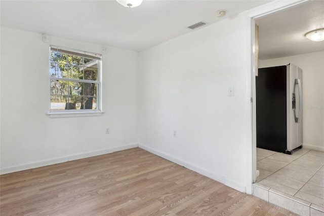 unfurnished room featuring baseboards, visible vents, and light wood-style floors