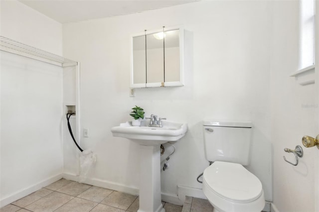 bathroom featuring toilet, tile patterned flooring, baseboards, and a sink