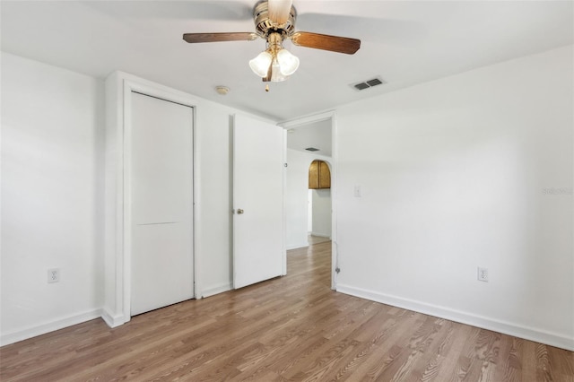 unfurnished bedroom with baseboards, visible vents, a ceiling fan, wood finished floors, and a closet