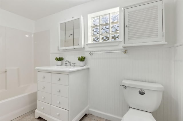 bathroom with a wainscoted wall, vanity, toilet, and tile patterned floors