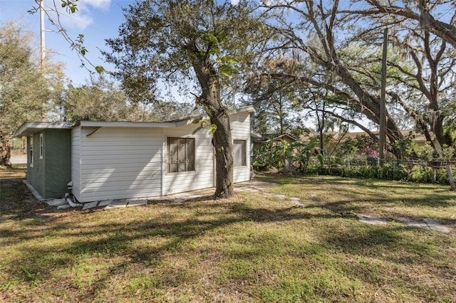 exterior space with fence, an outbuilding, and a yard