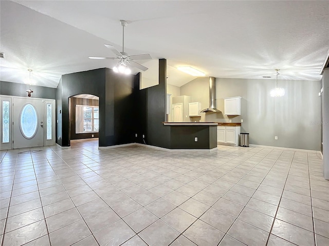 unfurnished living room featuring ceiling fan with notable chandelier, lofted ceiling, and light tile patterned floors