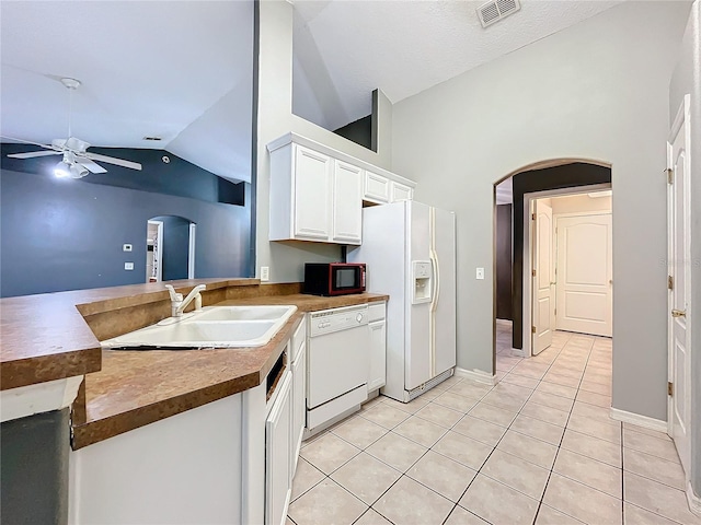 kitchen featuring light tile patterned flooring, lofted ceiling, sink, white cabinets, and white appliances