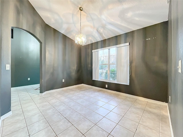 empty room with an inviting chandelier and light tile patterned floors