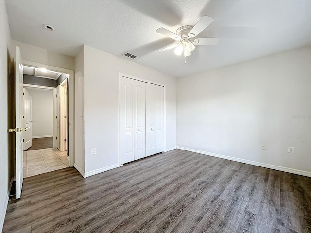 unfurnished bedroom with ceiling fan, wood-type flooring, a closet, and a textured ceiling