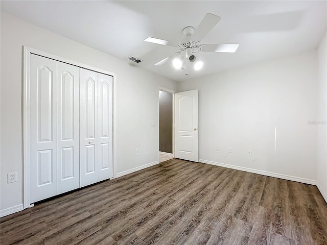 unfurnished bedroom featuring ceiling fan, dark hardwood / wood-style flooring, and a closet