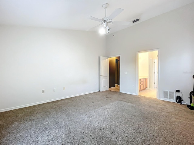 unfurnished bedroom featuring ensuite bathroom, high vaulted ceiling, light colored carpet, and ceiling fan