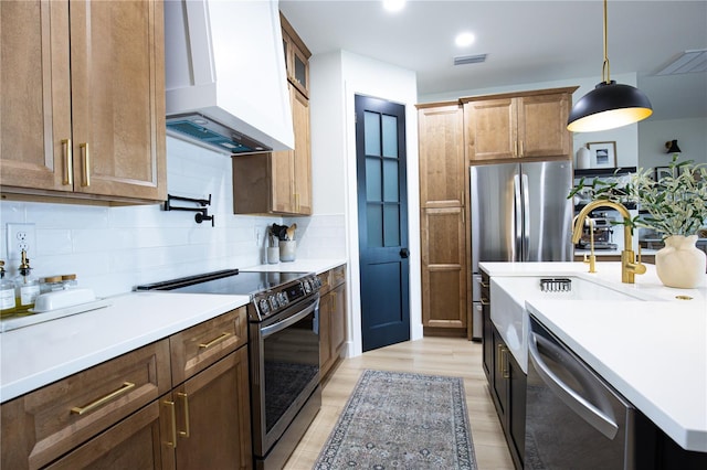 kitchen featuring sink, premium range hood, hanging light fixtures, backsplash, and stainless steel appliances