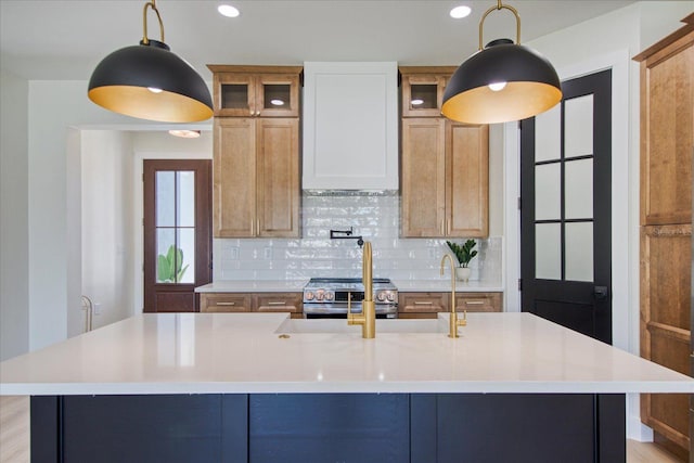 kitchen featuring a kitchen island with sink, pendant lighting, and backsplash