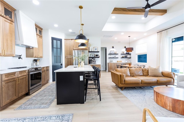 kitchen with premium range hood, appliances with stainless steel finishes, a breakfast bar, pendant lighting, and a center island with sink