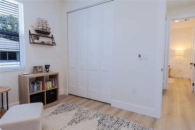 bedroom featuring multiple windows, light hardwood / wood-style flooring, and a closet