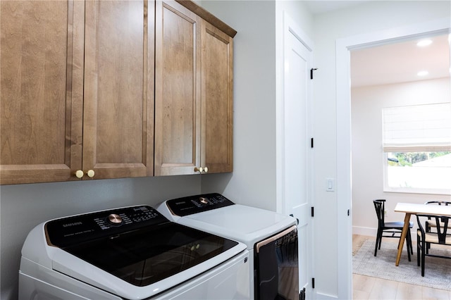 laundry area featuring cabinets, separate washer and dryer, and light hardwood / wood-style floors