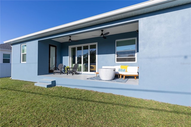 rear view of property with ceiling fan, a patio area, and a lawn