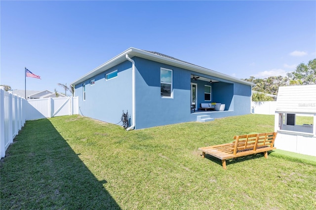 back of property with ceiling fan and a yard