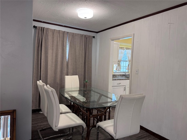 dining space with dark hardwood / wood-style flooring, sink, crown molding, and a textured ceiling