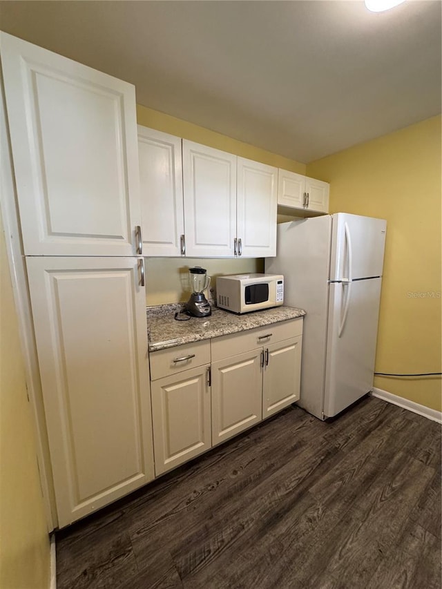 kitchen featuring light stone counters, white appliances, dark hardwood / wood-style floors, and white cabinets