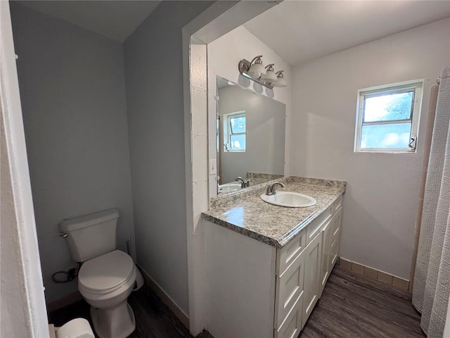 bathroom with vanity, a healthy amount of sunlight, hardwood / wood-style floors, and toilet