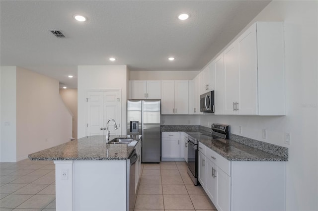 kitchen featuring appliances with stainless steel finishes, sink, dark stone counters, and white cabinets