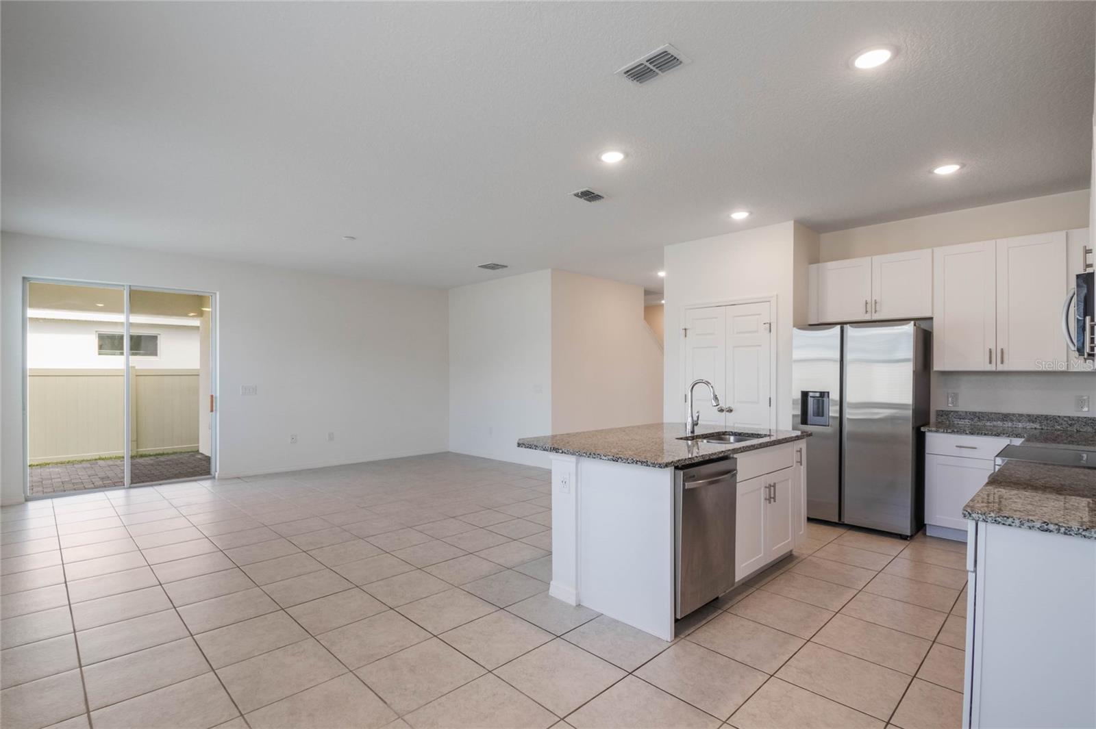 kitchen with appliances with stainless steel finishes, sink, white cabinets, dark stone counters, and a kitchen island with sink