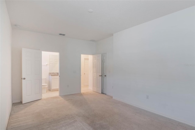 unfurnished bedroom with connected bathroom and light colored carpet