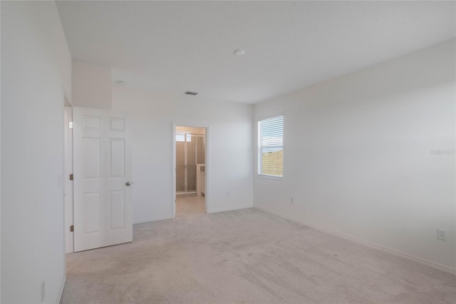 unfurnished bedroom featuring light colored carpet and ensuite bath