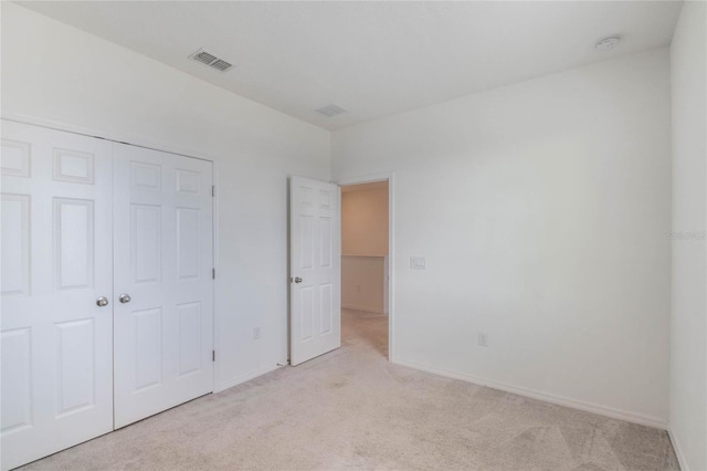 unfurnished bedroom featuring light colored carpet and a closet