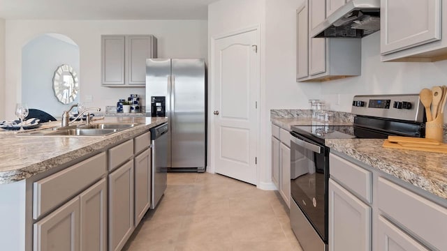 kitchen with sink, light tile patterned floors, appliances with stainless steel finishes, gray cabinets, and light stone countertops