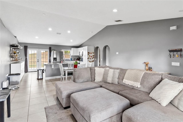 living room with light tile patterned floors, sink, vaulted ceiling, and french doors