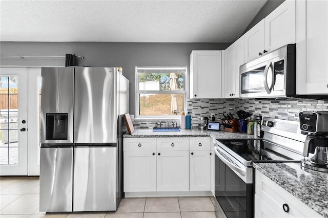 kitchen with white cabinetry, appliances with stainless steel finishes, light stone counters, and decorative backsplash