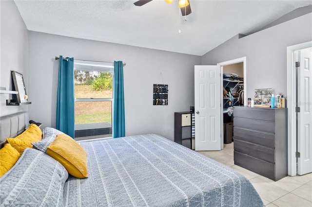 bedroom featuring lofted ceiling, light tile patterned floors, ceiling fan, a textured ceiling, and a spacious closet