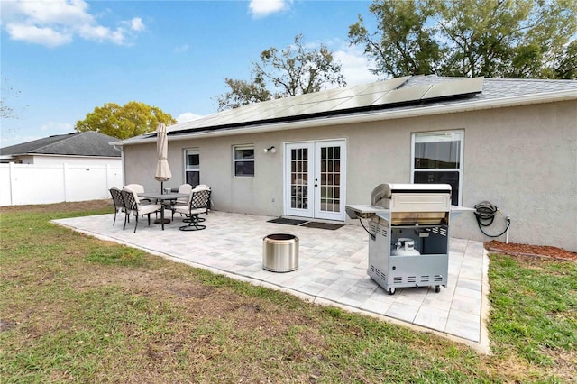 back of house featuring french doors, a patio, a lawn, and solar panels