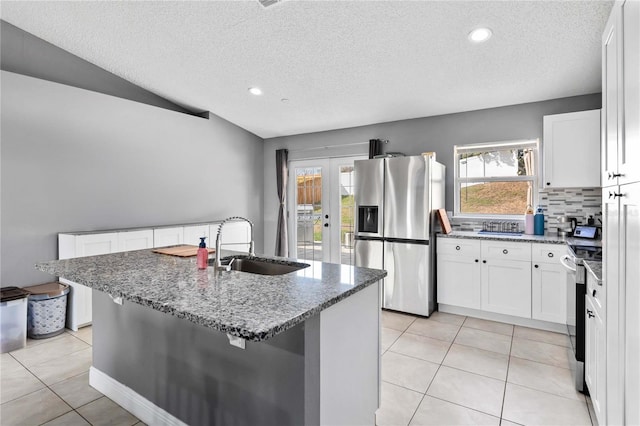 kitchen featuring appliances with stainless steel finishes, sink, white cabinets, a kitchen island with sink, and french doors