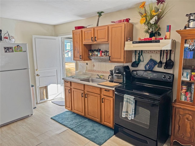 kitchen featuring black / electric stove, decorative backsplash, sink, and white fridge