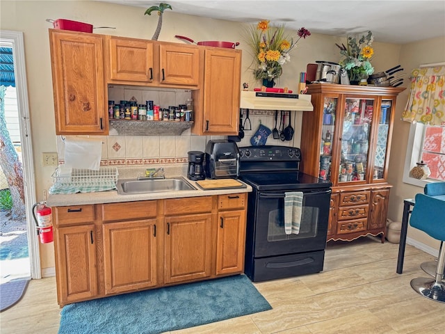 kitchen with black electric range oven, backsplash, and sink